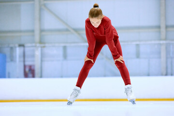 Girl in red sportswear, figure skating athlete standing on ice rink area and resting after hard...