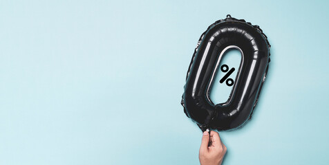 Hand holding black zero percentage balloon on blue background for special sale offer of shopping department store discount and banking interest rate concept.