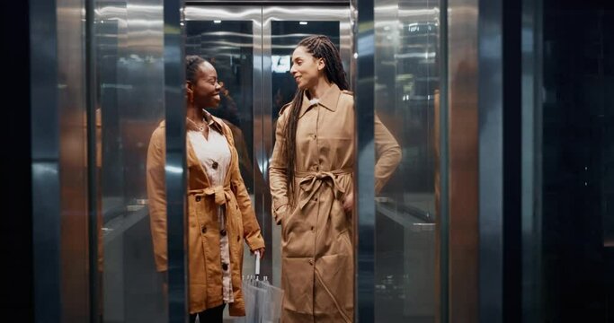 Elevator, business women and conversation in a office building at company going down. Female staff, happy and speaking of professional worker with a smile at hotel with workforce and job travel