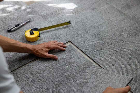 worker installing carpet tiles on the floor