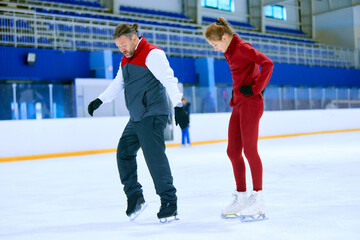 Professional skater, man training girl, learning figure skating activity on ice rink arena. Sport...