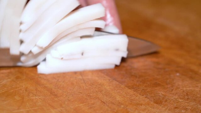 Slicing of salted pork fatback on cutting board, close-up. Ukrainian traditional food - salo