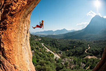 Rock climber descends from the route, the climber hangs on a rope, a rock in the form of an arch,...
