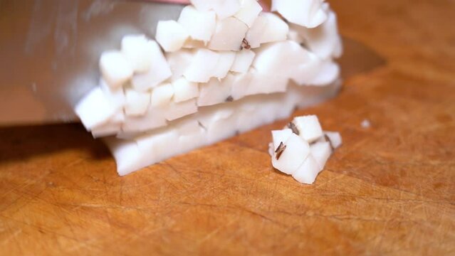 Slicing of salted pork fatback on cutting board, close-up. Ukrainian traditional food - salo