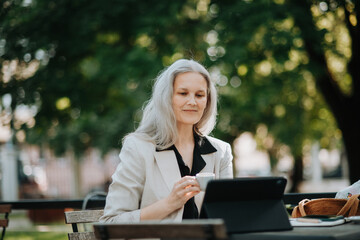 Portrait of beautiful female manager in middle age with gray hair working outdoors.