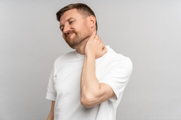 Unhealthy man suffering painful neck ache after sports exercise. Guy rubbing muscles to relieve pain or nerve spasm. Back pain and hernia, sedentary lifestyle concept. Health problems after 40.