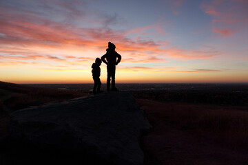 Fototapeta na wymiar Silhouettes of two young boys at dawn in Nose Hill Park in Calgary
