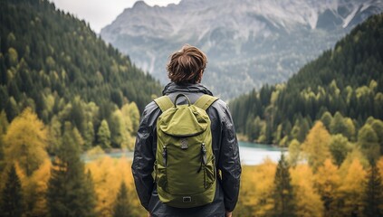 Hiking man with backpack looking at the lake and mountains in autumn