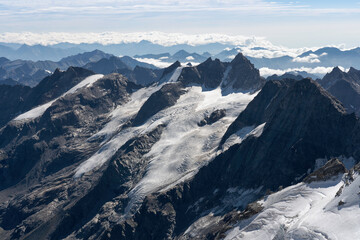 View from Gran Paradiso (National Park) mountain summit: glaciers of the massif and high rocky peaks. Mountains landscape. Global warming and climate change melting the glacier ice