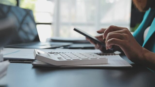 Close up Businesswoman using calculator and laptop for do math finance on wooden desk in office and business working background, tax, accounting, statistics and analytic research concept