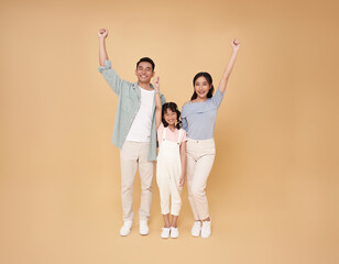 Happy celebrate asian parents family portrait standing with hands up  isolated on nude color...