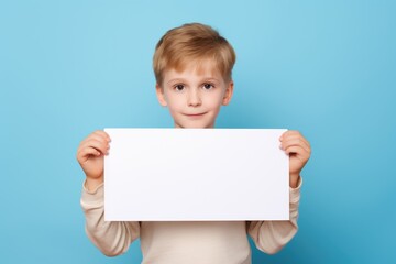 Fototapeta premium a handsome boy holding a blank placard sign poster paper for mock up in his hands