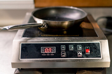 the induction stove on which the frying pan is placed is heated before frying the food in a...