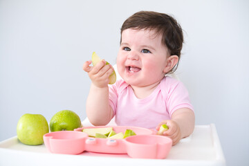 baby eating apple sitting in a high chair. weaning