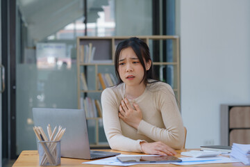 An Asian female has a heart attack pain, and tension-sick employee who is feeling heartache while...