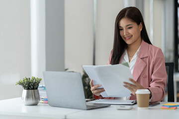 Businesswoman working in stacks of paper files to find and review unfinished documents in document folders to analyze planning and financial statistics Tax and investment market at desk.