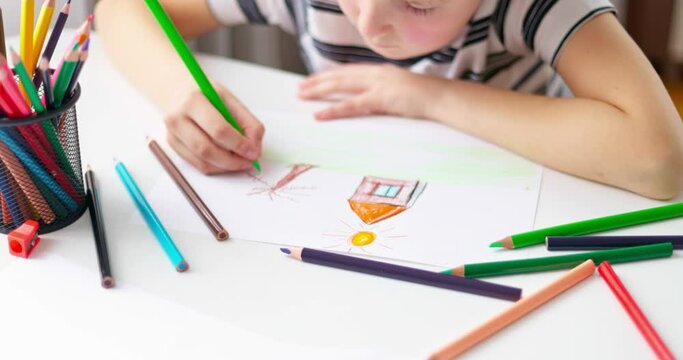 Cute boy drawing on a piece of paper with color pencils at home or classroom