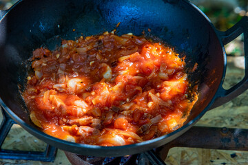 Italian pasta with bacon, tomato and a sprig of rosemary is cooked in a cast iron pot