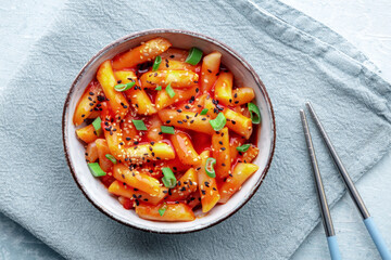 Tteokbokki or topokki, Korean street food, spicy rice cakes in red pepper gochujang sauce, shot from the top, with chopsticks