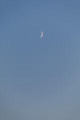 Bright Crescent Moon in Blue Afternoon Sky Background