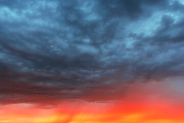 Dramatic sky at sunset, dangerous heavy gray red color clouds in sky, abstract sky and nature background