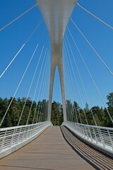 White modern steel cable bridge against blue sky.