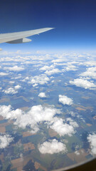 Fototapeta premium Beautiful view from above to the ground from the window of an airplane flying above the clouds. Shadows from clouds on the Earth's surface