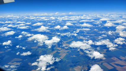 Fototapeta premium Beautiful view from above to the ground from the window of an airplane flying above the clouds. Shadows from clouds on the Earth's surface