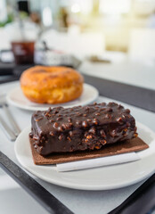 Cake Chocolate Jazz on a biscuit sheet served on a plate and donuts in a serving tray in a cafe dessert bakery or coffee shop.