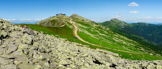 Mountain landscape on a hiking trail in the Low Tatras, Slovakia. View of mountain peaks and valleys while hiking along a mountain ridge. Slopes covered with alpine vegetation, summer sunny day.