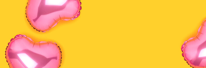 Banner with pink foil balloons in a heart shape scattered on a yellow background.