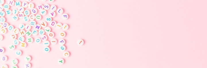 Banner with beads with letters scattered on a pink background. Creative concept.