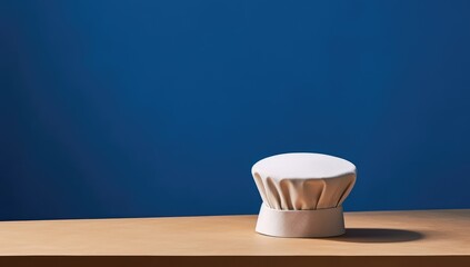 photo of a chef's hat on a table with a blue colored background, in the style of minimalist backgrounds, 21st century, dark beige and white, cabincore, high resolution, made with Generative AI