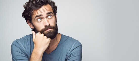 30 year old man with dark hair and beard posing against white background with copy space - obrazy, fototapety, plakaty