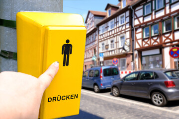 female hand presses yellow button to turn on traffic light pedestrian crossing, in German PRESS,...