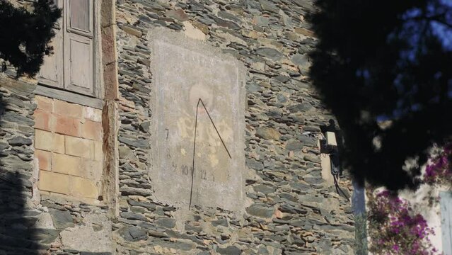 reloj de sol en la pared de una casa de piedra