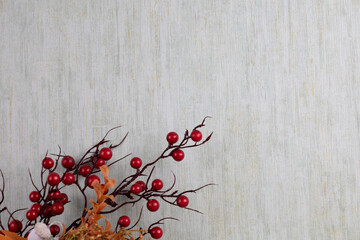 Branch of red berries and dry branch on grey textured background with copyspace