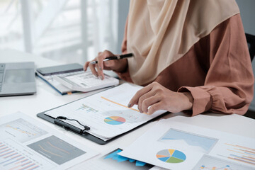 muslim business woman brown hijab working about financial with business report and calculator in home office.