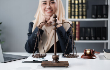 A female Muslim lawyer is sitting in the office doing paperwork for a client.