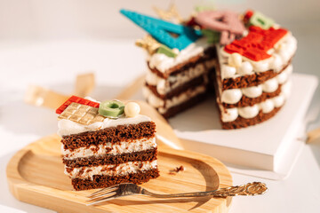 Layer cake with white filling decorated with school supplies made of chocolate in front of the window