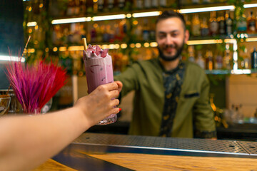 bartender hands a fresh bright tasty cocktail to a guest in a bar or restaurant close-up of hands