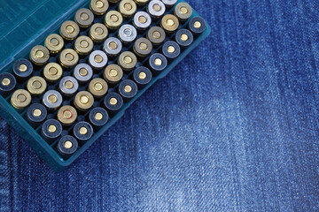 Plastic box containing 9 mm ammunition on a jeans background. soft and selective focus.  