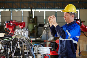 electrician engineer or worker checking electric cable in robot factory