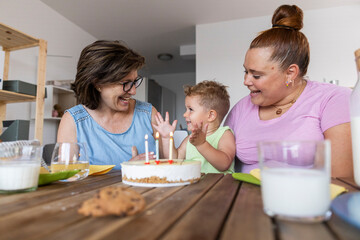 happy family of mother and grandmother and little boy celebrating birthday. multigeneration people in the living room of their house