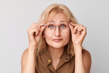 Portrait of 50 year old lady squinting in glasses isolated on white studio background. Vision check...