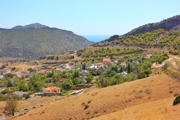 View of a small town lost among green hills and rocks. Point summer day, blue sky, a pleasant place for tourism.