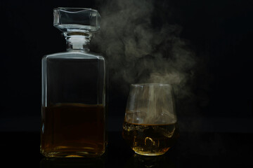 Cocktail whiskey drink on ice isolated at black with smoke