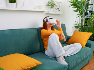 woman sitting on sofa relaxing and playing VR and using futuristic artificial intelligence at home.. the concept of metaverse, virtual reality, future, technology, and internet of things.