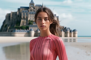 Obraz premium Medium shot portrait photography of a tender girl in her 20s wearing a vibrant rash guard at the mont saint-michel in normandy france. With generative AI technology