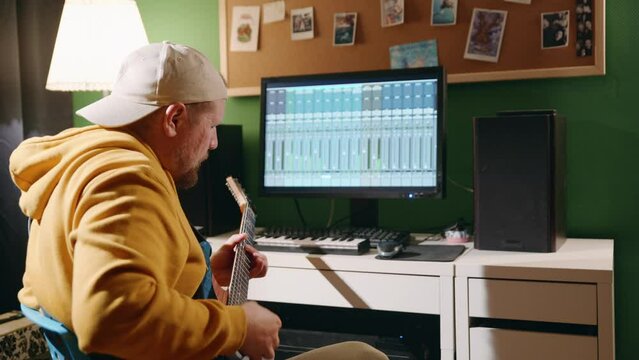 Music production studio. Caucasian man recording electro guitar song music. Producer man working in the recording studio with computer and mixer creating music in sound recording studio. Professional